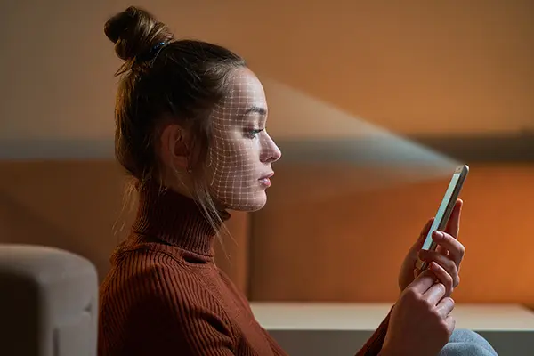 A girl holding a phone has face mesh and her face is being analyzed with facial analysis